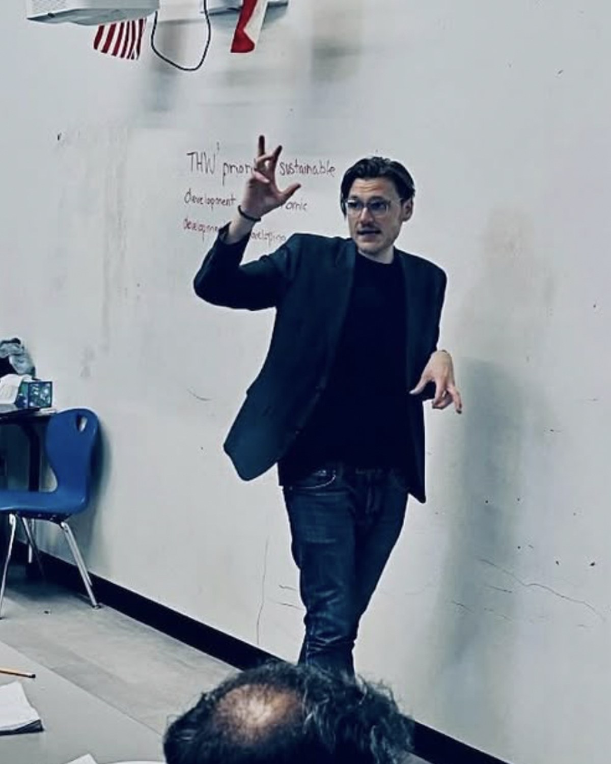 Mr. Miha Andrič leading a debate workshop beside a motion written on the wall